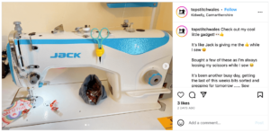 An Instagram post screenshot of a sewing machine with a hand-shaped gadget to hold scissors